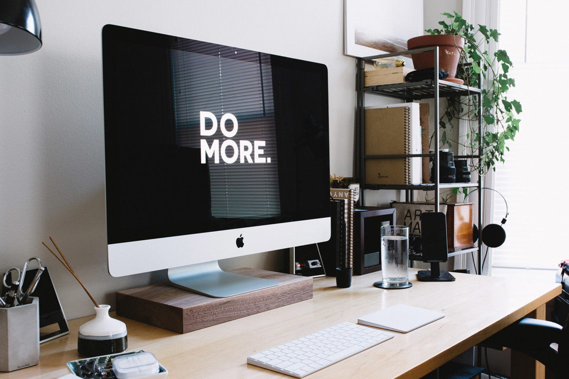 An einem Arbeitsplatz steht ein Monitor dessen Bildschirmschoner sagt: Do More.