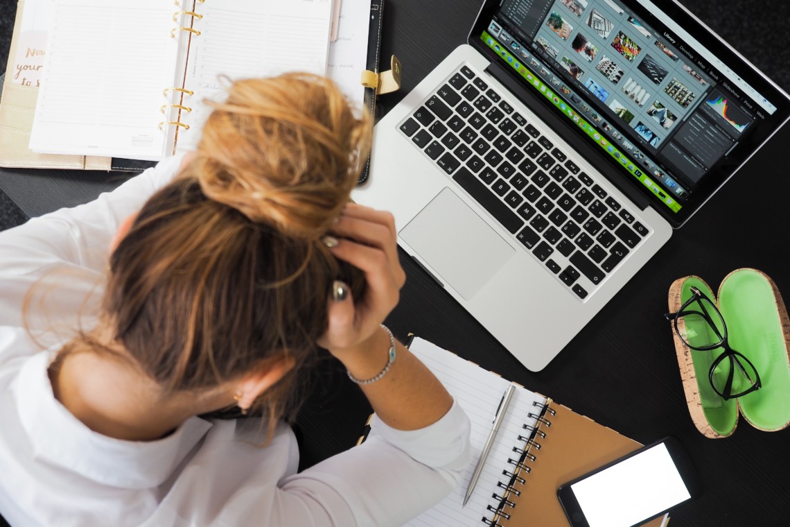 Stress am Arbeitsplatz. Eine Frau beugt sich gestresst über ihren Computer.