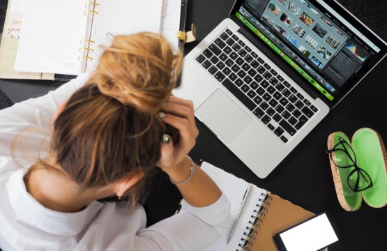 Stress am Arbeitsplatz. Eine Frau beugt sich gestresst über ihren Computer.