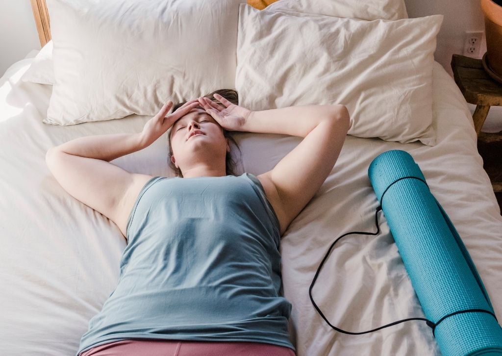 Antriebslosikeit Frau liegt neben Yogamatte auf dem Bett